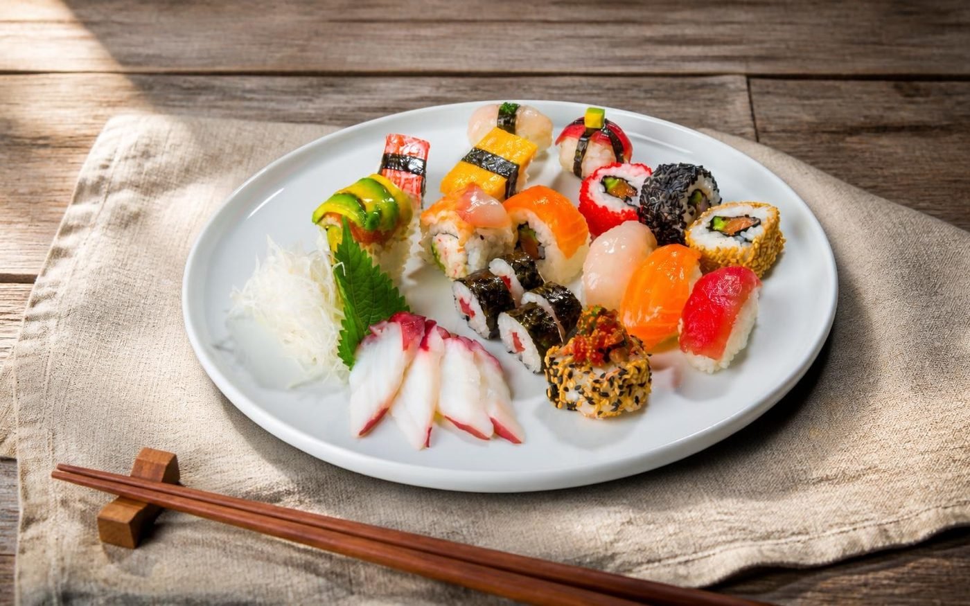 An assorted plate of nigiri, sashimi and rolls on a cedar table