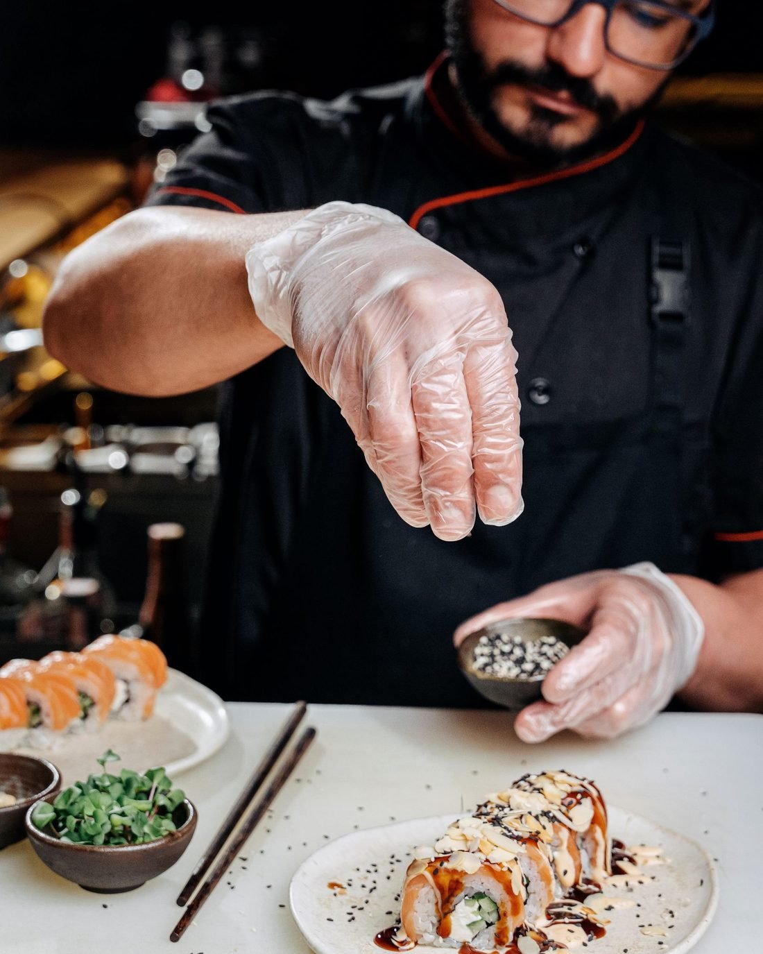 A sushi chef in gloves finishing a roll